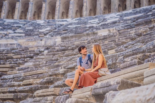 Happy couple man and woman tourists explores Aspendos Ancient City. Aspendos acropolis city ruins, cisterns, aqueducts and old temple. Aspendos Antalya Turkey. turkiye.