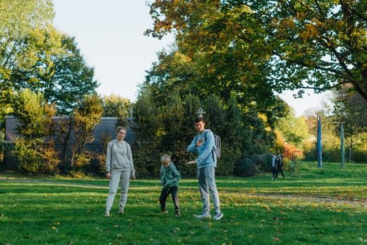 a family mom and 2 sons are having fun, running in the park and jumping. Sons, children, mom, run, play, rejoice, enjoy nature in summer. Family teamwork. Happy family team, running together in field, happily waving their hands. Group of people of different ages. happy family, mom and two sons on an emotional walk. Running and enjoying life in a green field in the park, blue sky, nature.