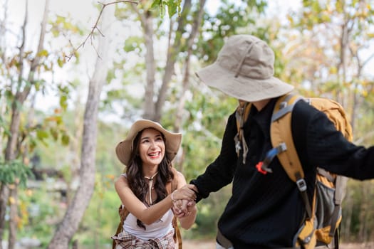 Cheerful romantic lesbian couple traveler with backpack on their backs go hiking through the forest in the mountains in summer.