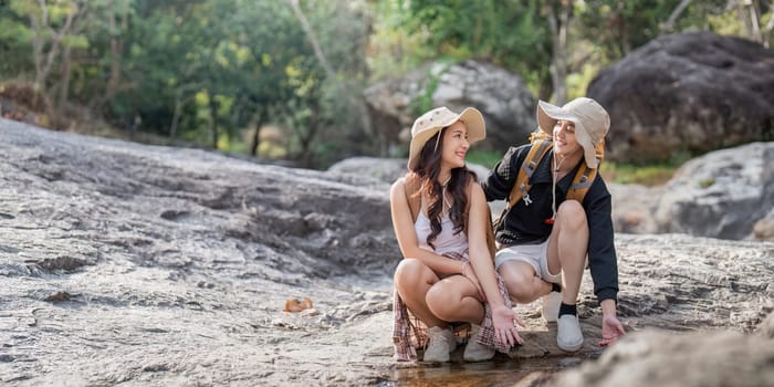 Cheerful romantic lesbian couple traveler with backpack on their backs go hiking through the forest in the mountains in summer.