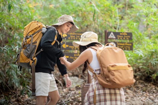 Cheerful romantic lesbian couple traveler with backpack on their backs go hiking through the forest in the mountains in summer.