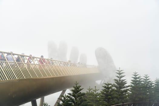 Danang, Vietnam - June 27, 2023: The Golden Bridge is lifted by two giant hands in the tourist resort on Ba Na Hill in Danang, Vietnam.