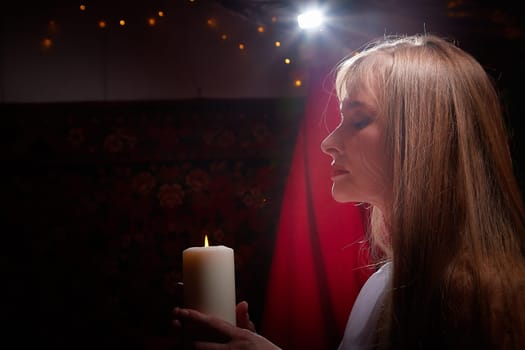 Beautiful arabian girl with candles in red room full of rich fabrics and carpets in sultan harem. Photo shoot of woman an oriental style odalisque. Model poses in sari as caring wife and hostess