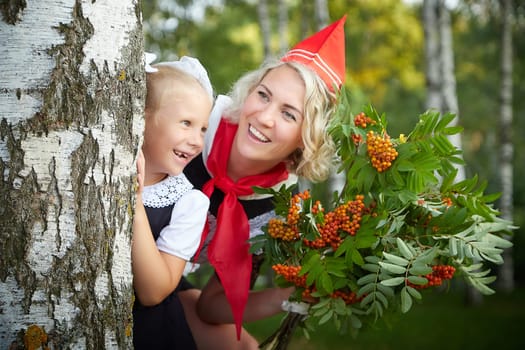 Young and adult schoolgirl on September 1, mother and daughter having fun and joy. Generations of schoolchildren of USSR and Russia. Female pioneer in red tie and October girl in modern uniform