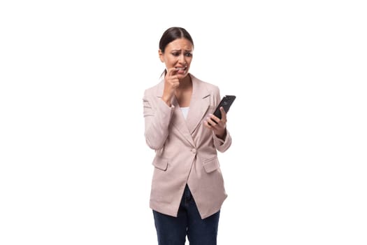 young slender brunette business woman with ponytail dressed in a jacket communicates on the phone in social networks.