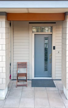 Ground level entrance of residential apartment in low-rise building with wooden seat beside
