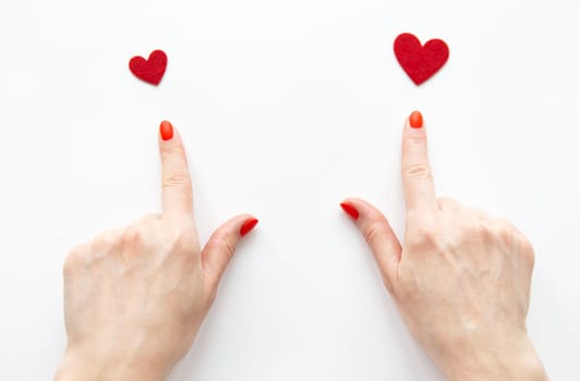 The girl shows her hand to a small and large red heart. The concept of care and love