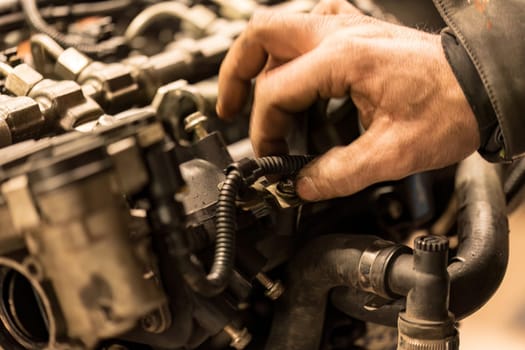 Photo capturing a mechanic's grimy hand on a car engine, highlighting the reality of automotive work.