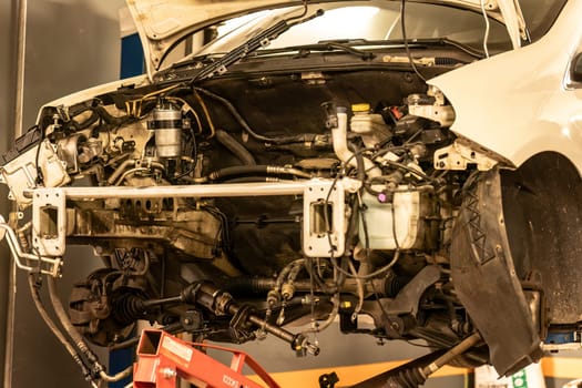 Photo of a car in a workshop missing its engine, awaiting repair, showcasing automotive servicing.