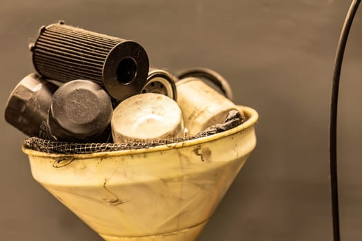 Photo of old, exhausted oil filters in a workshop, symbolizing hazardous waste disposal in automotive maintenance.