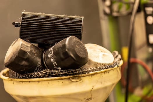 Photo of old, exhausted oil filters in a workshop, symbolizing hazardous waste disposal in automotive maintenance.