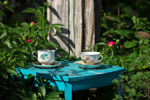 White China Teacups on Blue Table in Garden Double as Garden Art and Bird Baths. High quality photo