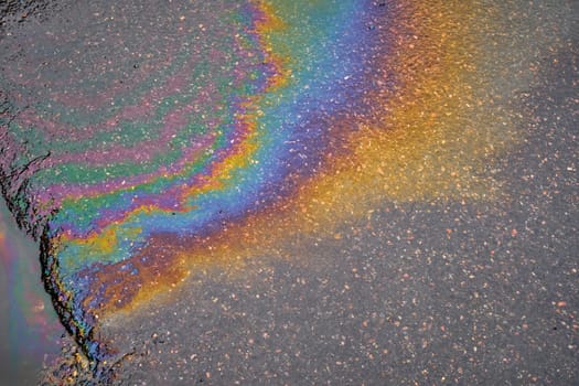 Leakage of oil or gasoline from a car onto a wet asphalt road. Environmental pollution concept