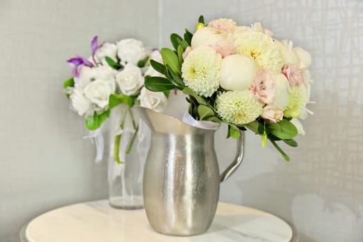 Beautiful Wedding Bouquets in Pitchers of Water on End Table Indoors. High quality photo