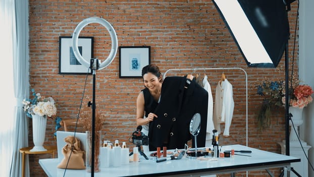 Woman influencer shoot live streaming vlog video review clothes social media or blog. Happy young girl with apparel vivancy studio lighting for marketing recording session broadcasting online.