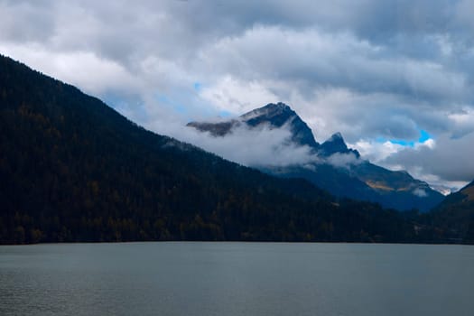 Clouds and Serenity: A Mountain Lake Reflects the Overcast Autumn Skies, Encircled by Misty Alpine Peaks. High quality photo