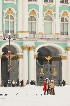 Russia, Saint Petersburg, 30 December 2023 - Actors in the role of Peter the Great and Catherine the Great walk across the square Palace at snowfall, The Hermitage building on background. High quality photo