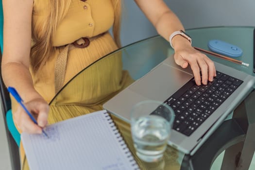 Beautiful pregnant woman working on laptop. Young businesswoman working in her office.