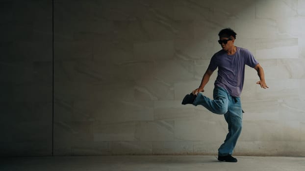 Skilled smart street dancer practice b-boy movement in building with gray background. Young handsome attractive choreographer perform energetic and active movement. Outdoor sport 2024. Sprightly.