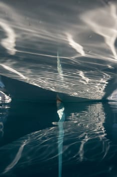 the stern of the sailboat and the rudder feather in the azure water, sun reflections are on glossy board of moored sail boat, Monaco, Monte-Carlo, tranquillity in port Hercules at sunny day. High quality photo