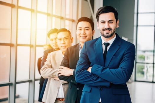 Confidence radiates from the group portrait of young businesspeople and a businessman indoors. With crossed arms, they represent a successful, diverse team and a thriving startup.