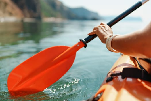 Kayak paddle sea vacation. Person paddles with orange paddle oar on kayak in sea. Leisure active lifestyle recreation activity rest tourism travel.