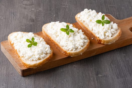 Bread with curd cheese on wooden board.