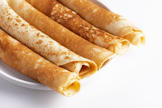 Thin pancakes rolled into a roll on a plate. The concept of a delicious breakfast or Maslenitsa.