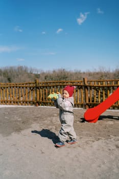 Little girl with a toy car walks through the playground. High quality photo