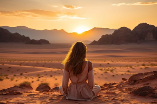 A woman looks at a deserted canyon while sitting on a rock.