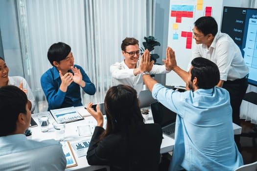 Analyst team leader celebrate and high five together with his colleague after successful data analysis meeting using FIntech software power with business intelligence or BI dashboard. Prudent