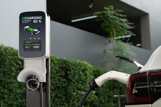 EV electric car charging in green sustainable city outdoor garden in summer. Urban sustainability lifestyle by green clean rechargeable energy of electric BEV vehicle innards