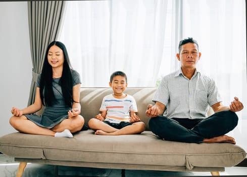 Serene family bonding, parents and their little son practice yoga seated in lotus pose on a sofa. Encouraging harmony balance and tranquility within the home.