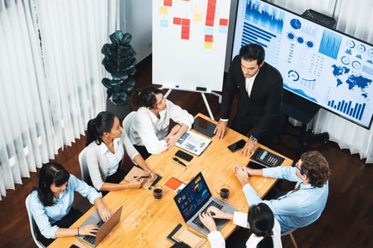 Wide top view of diverse group of business analyst team analyzing financial data report paper on meeting table. Chart and graph dashboard by business intelligence analysis. Meticulous