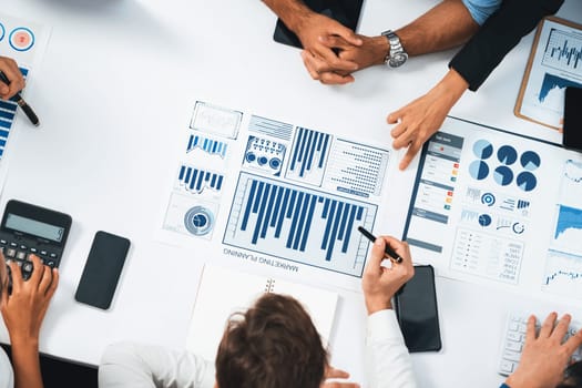 Top view analyst team utilizing BI Fintech to analyze financial data at table in meeting room. Analytic BI dashboard power on paper for business insight and strategic marketing planning. Prudent