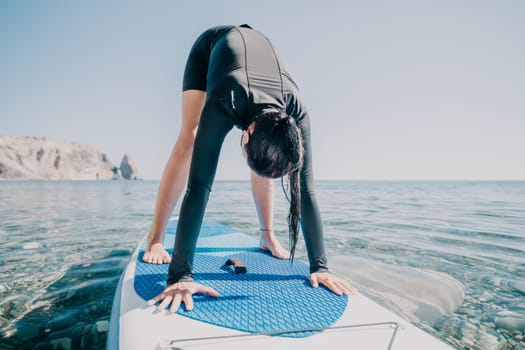 Woman sup yoga. Middle age sporty woman practising yoga pilates on paddle sup surfboard. Female stretching doing workout on sea water. Modern individual hipster outdoor summer sport activity