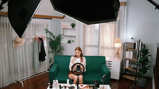 Woman influencer shoot live streaming vlog video review makeup prim social media or blog. Happy young girl with cosmetics studio lighting for marketing recording session broadcasting online.