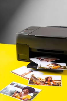 Printer printing colorful photos of people close up, yellow background, studio shot