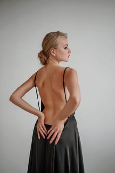 Woman in black dress on white background in the studio. Elegant lady in long gown. Sexy girl in formal prom dress