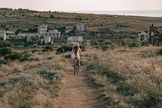 A woman cyclist on a mountain bike looking at the landscape sea. Adventure travel on bike