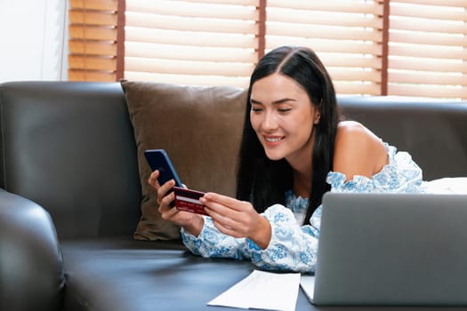 Young woman using online payment app and digital wallet on smartphone to pay with credit card. E commerce shopping and modern purchasing via mobile internet. Blithe