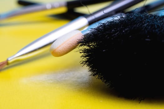 Makeup brushes on a yellow background close up