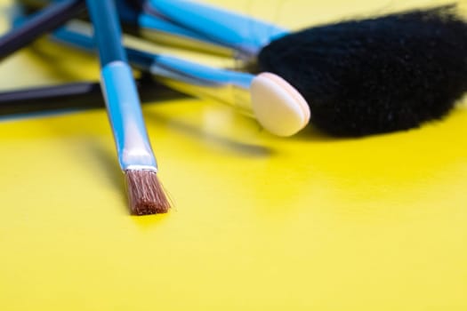Makeup brushes on a yellow background close up