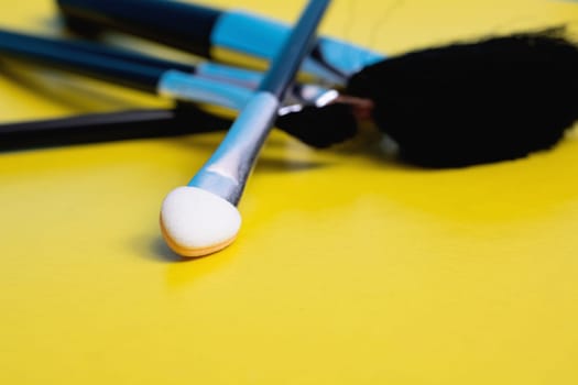 Makeup brushes on a yellow background close up
