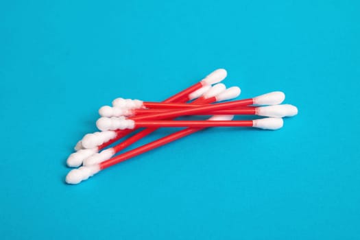 A pile of red cotton buds on a blue background close up