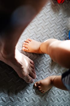 Bare feet of a father and a son on the ground.