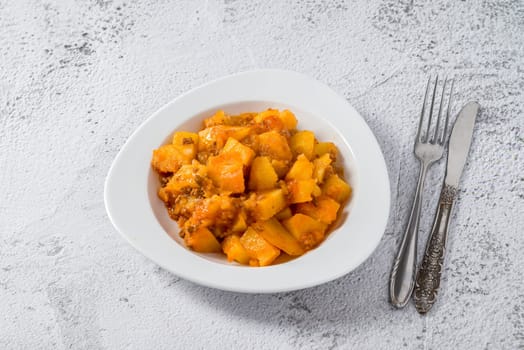 Minced meat and potato dish on white porcelain plate on stone table