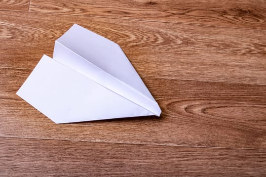 White paper plane on a wooden table close up