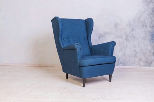 Classic blue chair on white wall background with swirl decorations. Studio interior.