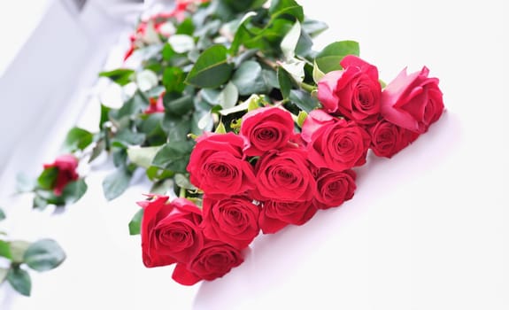 Beautiful bouquet of red roses lies on white background. Dutch fragrant rose flowers concept